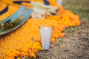White votive candle beside marigold