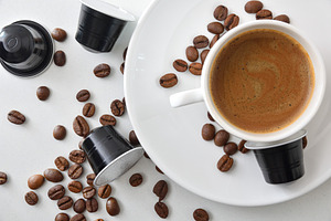 Espresso cup on a plate on white table with capsules, a Food & Drink Photo by Davizro's Market