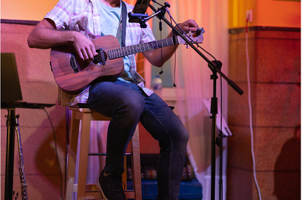 Man sitting on stage with an ukulele, a Person Photo by Barcelona_dreams