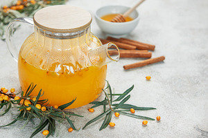 Glass teapot with sea buckthorn tea, honey and cinnamon sticks o, a Food & Drink Photo by Olena Rudo