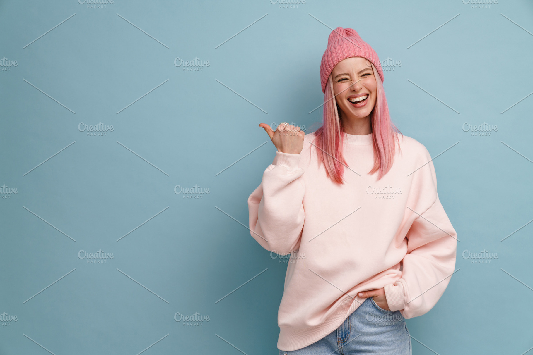Young woman wearing pink hat laughing and pointing finger aside, a Person Photo by Dean Drobot