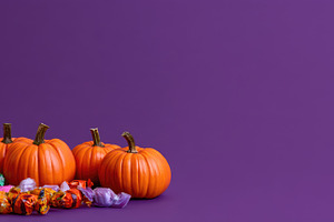 Halloween pumpkins and candy on purple copy space