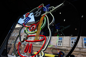 Colorful neon sign reflecting from a storefront window in urban surroundings, a Photo by AS photostudio