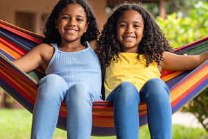 Two girls sitting together on a hammock in the backyard of a hou, a Person Photo by DanFLCreativo