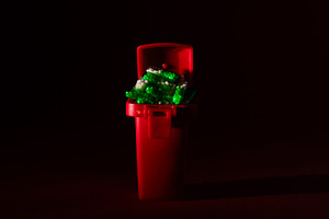 Small red trash bin filled with green and white plastic pieces, isolated on a d, a Health & Medical Photo by Ales Munt