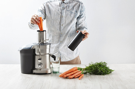 Fresh juice near industrial juicer featuring salmon, carrot, and juicer, a Food & Drink Photo by DeRepente