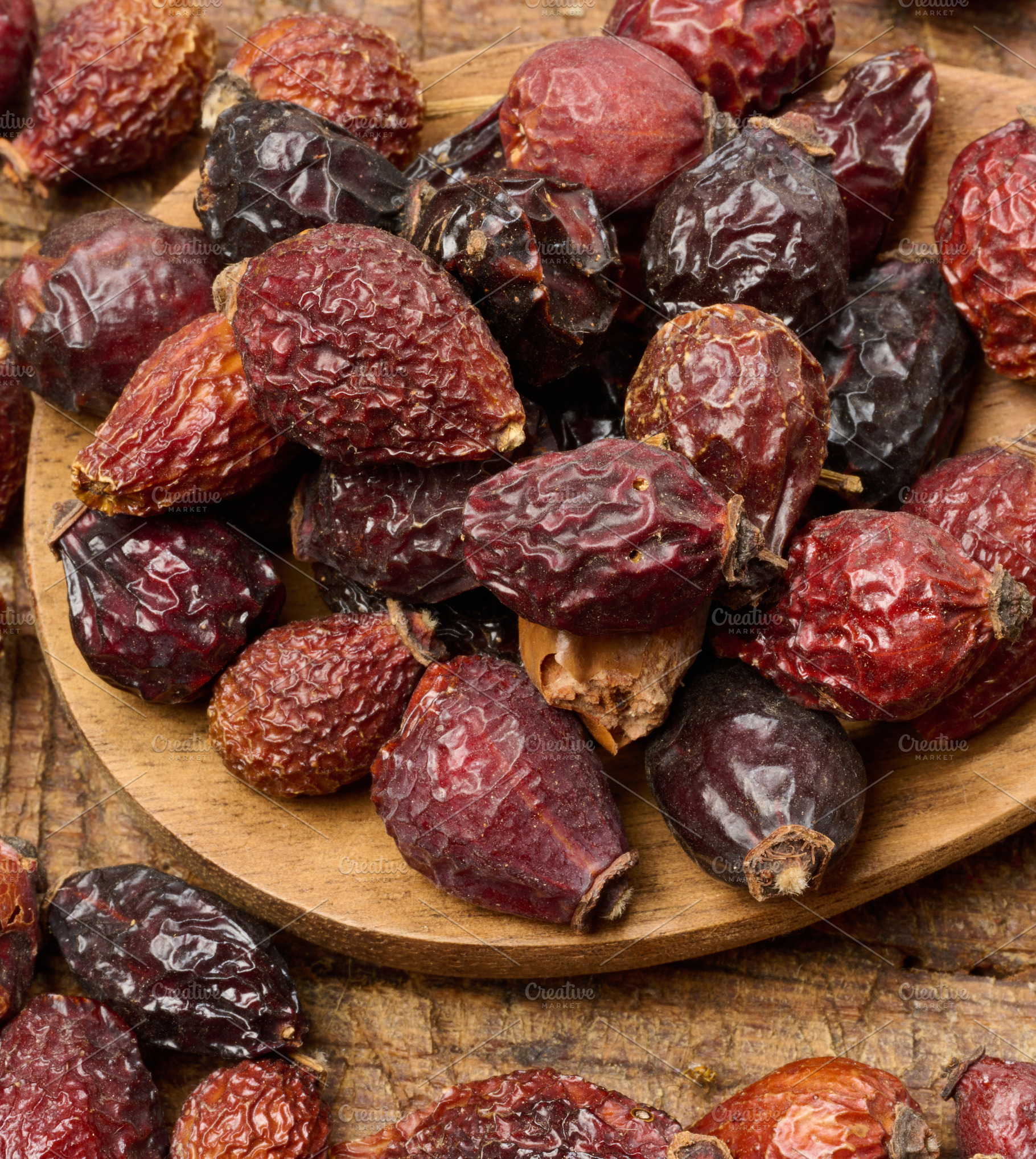 Dried rosehip fruits in a wooden spoon and on a table close-up., a Food & Drink Photo by ndanko