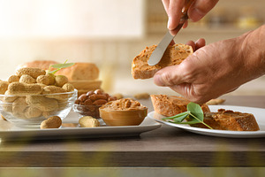 Hands spreading peanut butter on slices of bread in kitchen, a Food & Drink Photo by Davizro's Market