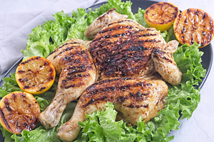 Grilled spatchcocked chicken with lemon garlic marinade on lettuce with lemon h, a Food & Drink Photo by iuliia_n