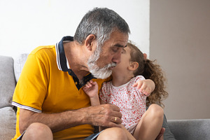 Grandfather giving an affectionate kiss to his smiling granddaughter, a Person Photo by etorres69