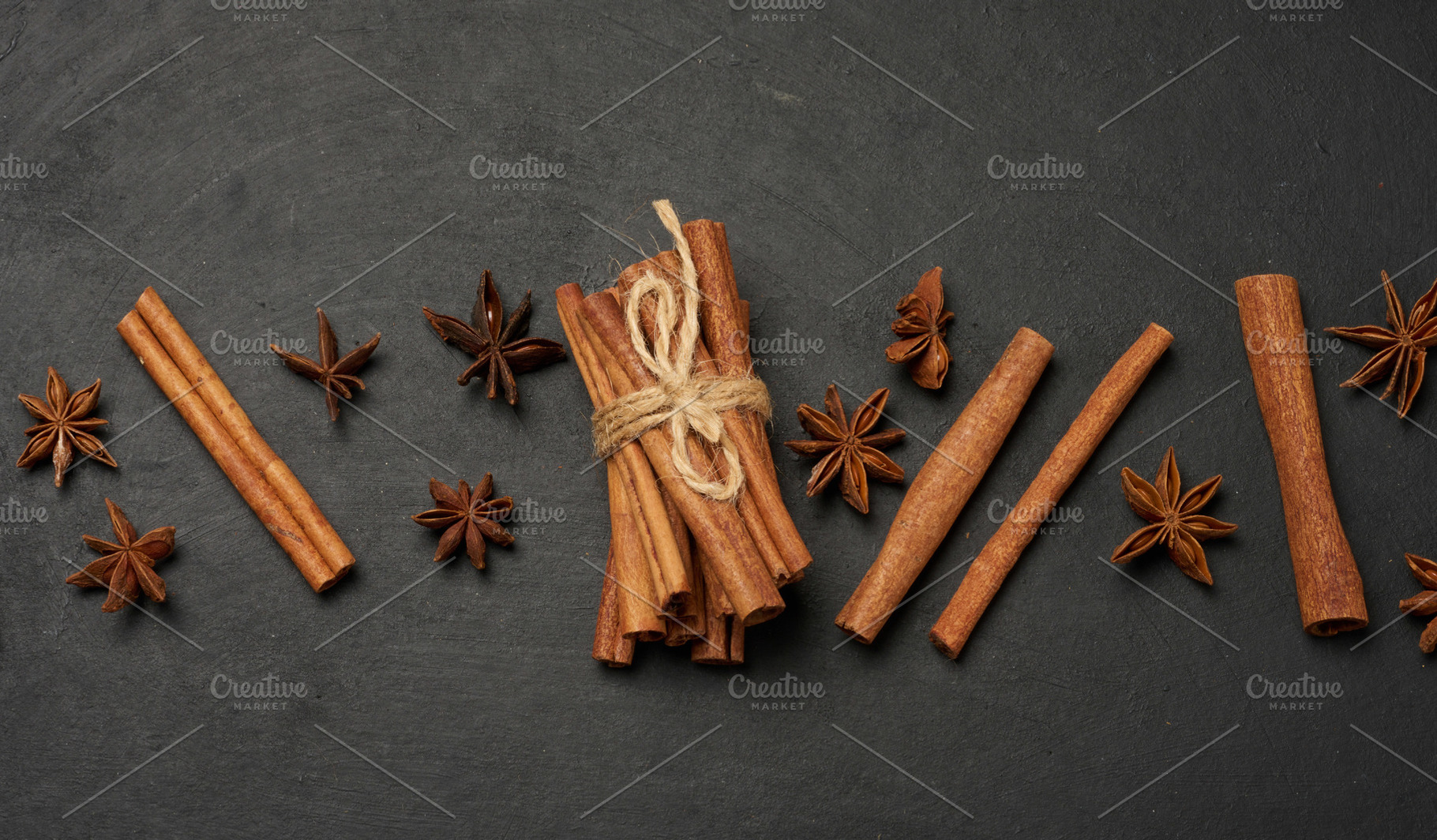 Cinnamon sticks and star anise are scattered on a dark, textured, a Food & Drink Photo by ndanko