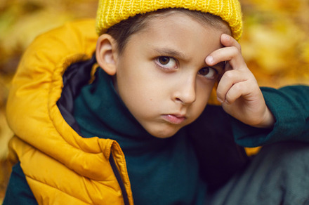 portrait of a fashionable serious child boy autumn sitting on a trail in orange, a Person Photo by SaulichPhoto