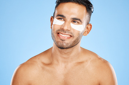 Skincare, eyes patch and man beauty, dermatology and body cosmetics of wellness, facial treatment or collagen eye care mask on studio blue background. Happy arab guy use healthy face for dark circles, a Photo by Peopleimages.com