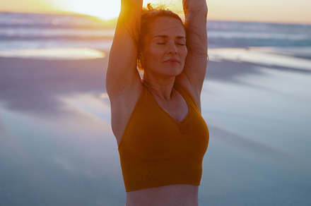 relaxed active sports woman at beach at sunset stretching, a Sports & Recreation Photo by Alliance Images