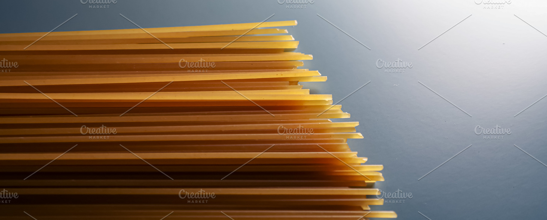 Dry spaghetti pasta noodles forming a pattern on a gray background, raw Italian, a Photo by Studio ANNA