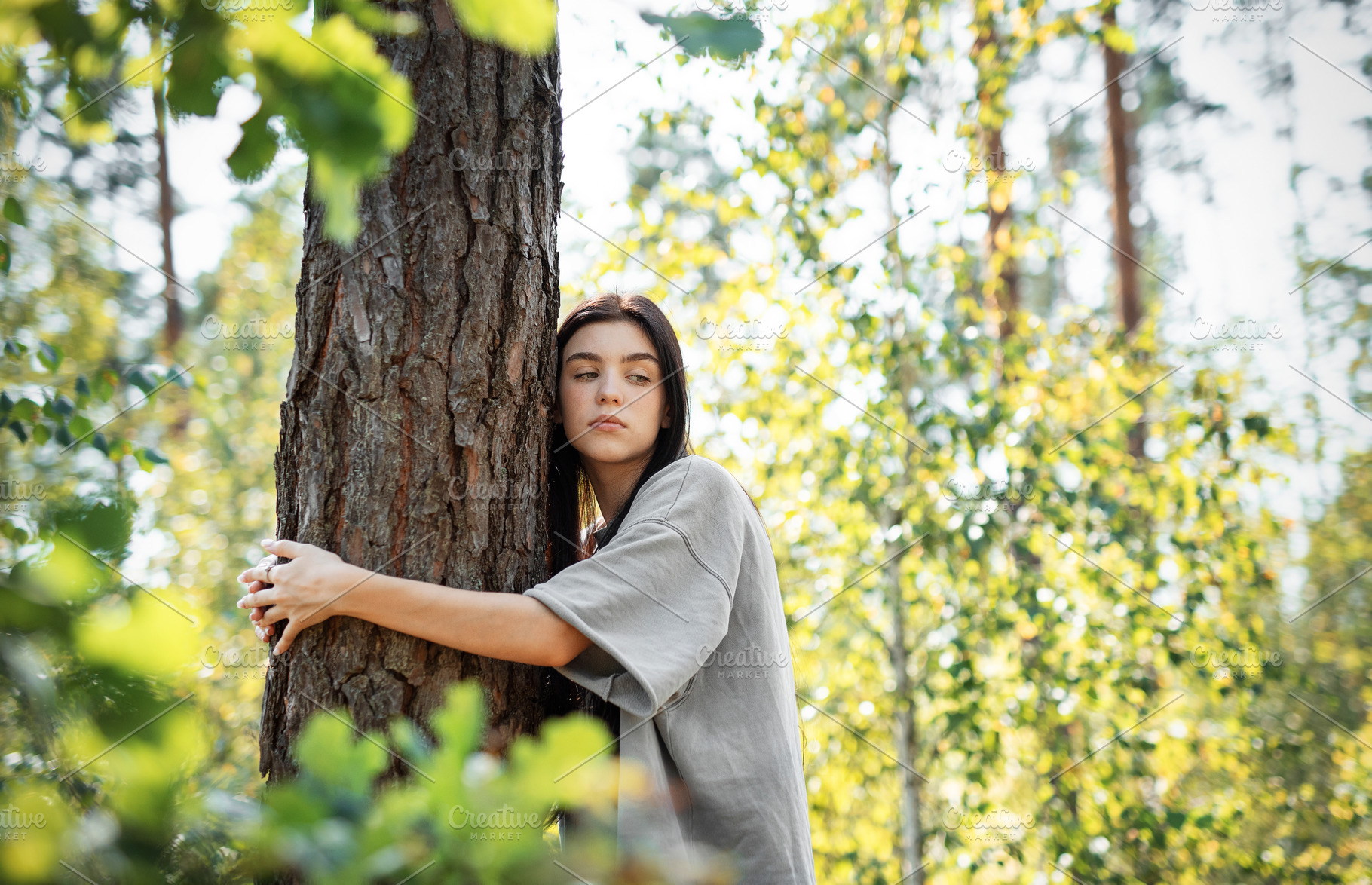 Young woman enjoying a peaceful moment by a tree in a lush green, a Person Photo by Olena Rudo