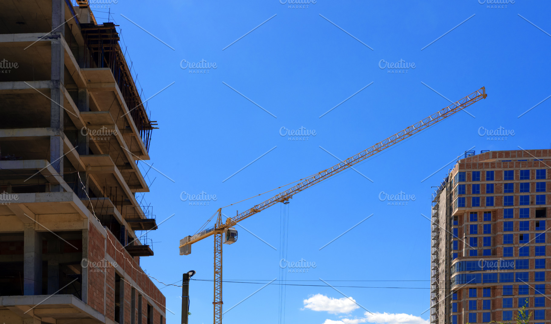 Tall yellow tower crane operating between an unfinished building, an Architecture Photo by Ales Munt