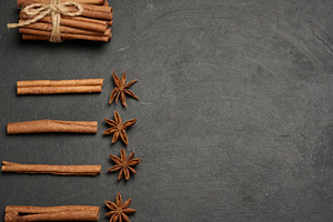 Cinnamon sticks and star anise are scattered on a dark, textured, a Food & Drink Photo by ndanko