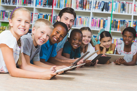 Teacher and kids lying on floor using digital tablet in library, a Photo by wavebreak