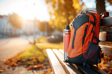Backpack with integrated solar panel sits on bench during autumn sunset in city, a Beauty & Fashion Photo by AlyaAnd