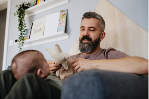 Father holding baby boy on his lap., a Person Photo by HalfPoint