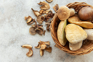 Fresh mushrooms overflowing from wicker basket onto table with d, a Food & Drink Photo by Olena Rudo