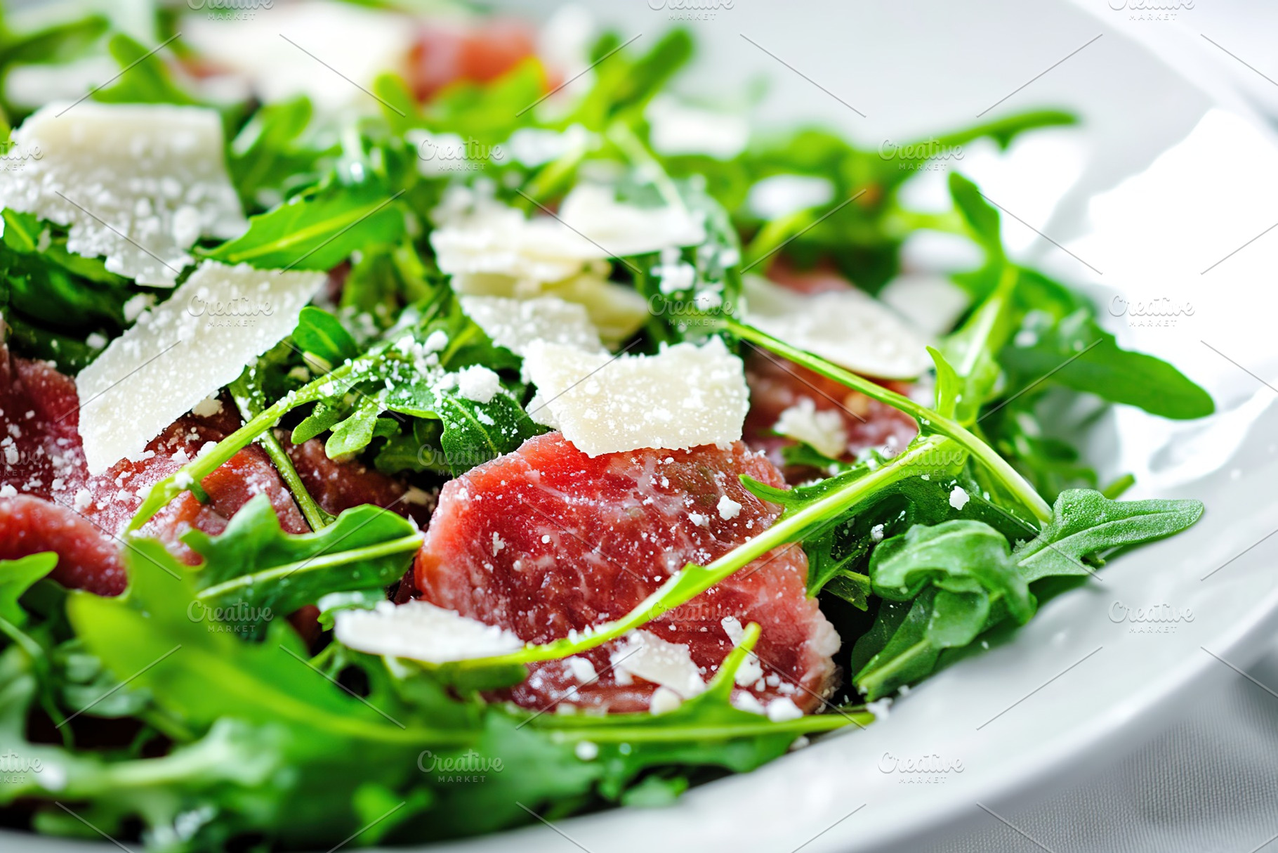 Delicious beef carpaccio served with fresh arugula and shaved cheese garnishes, a Food & Drink Photo by AlyaAnd