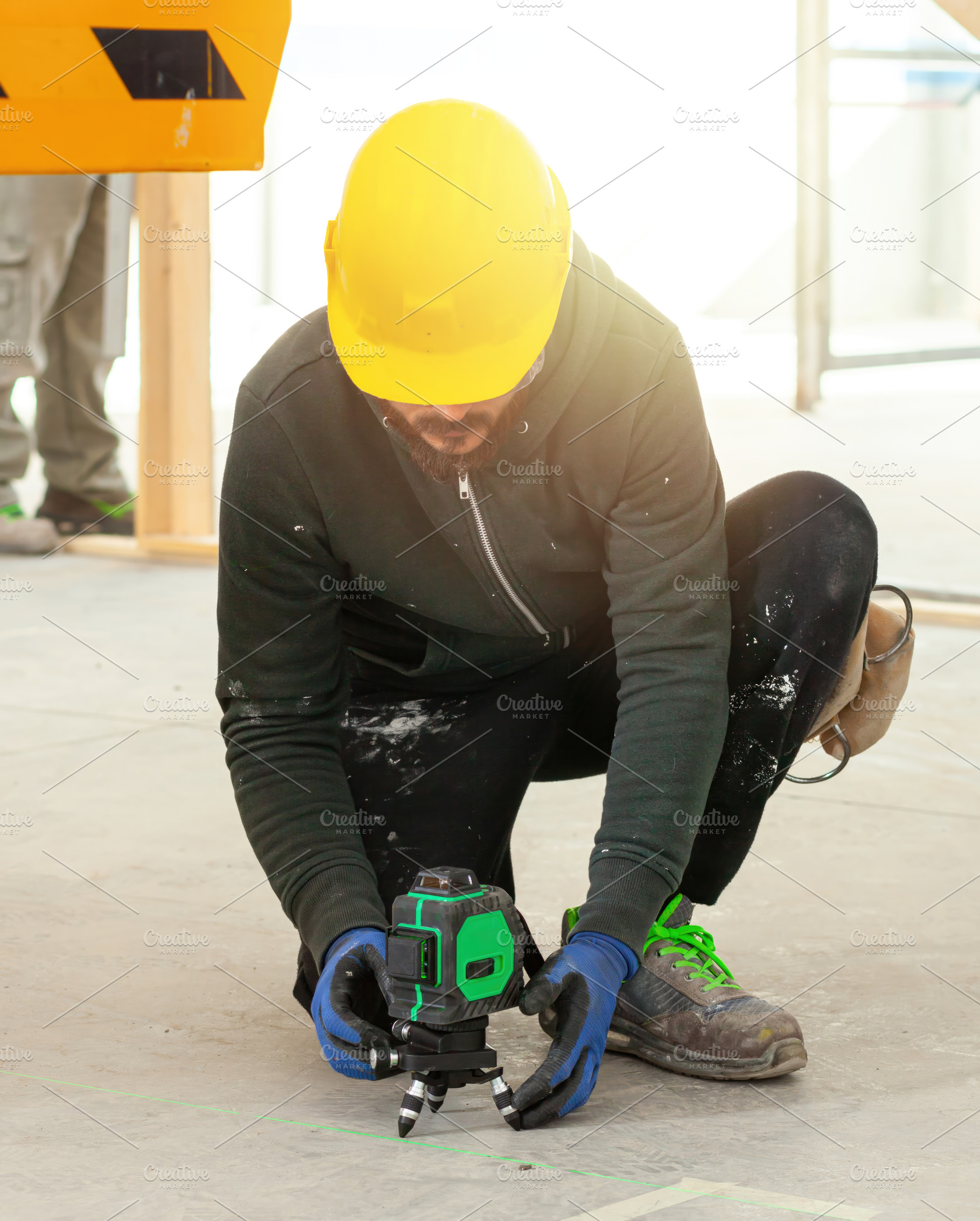 Construction worker using rotating laser level on tripod at construction site, an Industrial Photo by Antonio Gravante Market