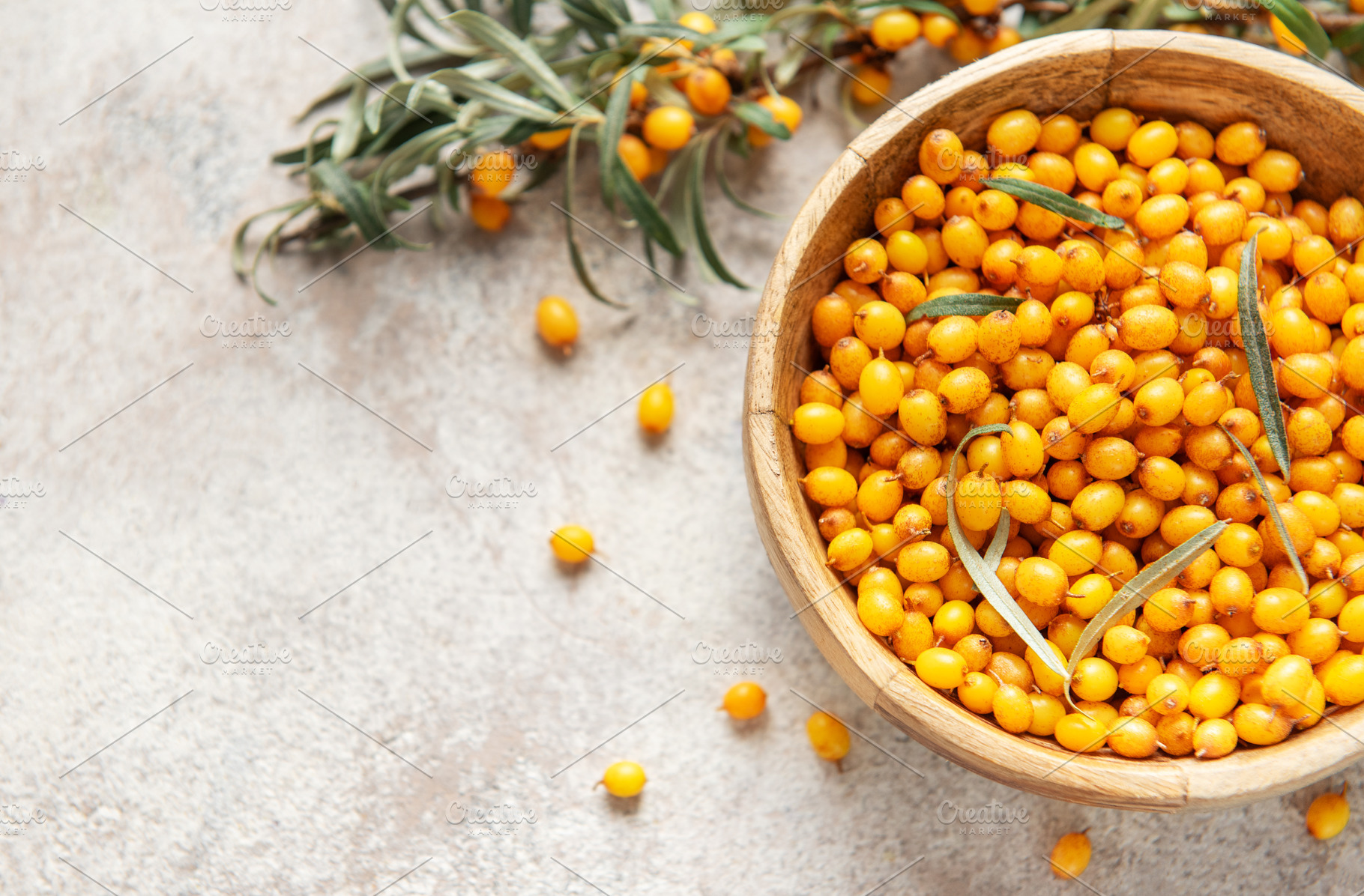 Sea buckthorn berries filling wooden bowl on table, a Food & Drink Photo by Olena Rudo