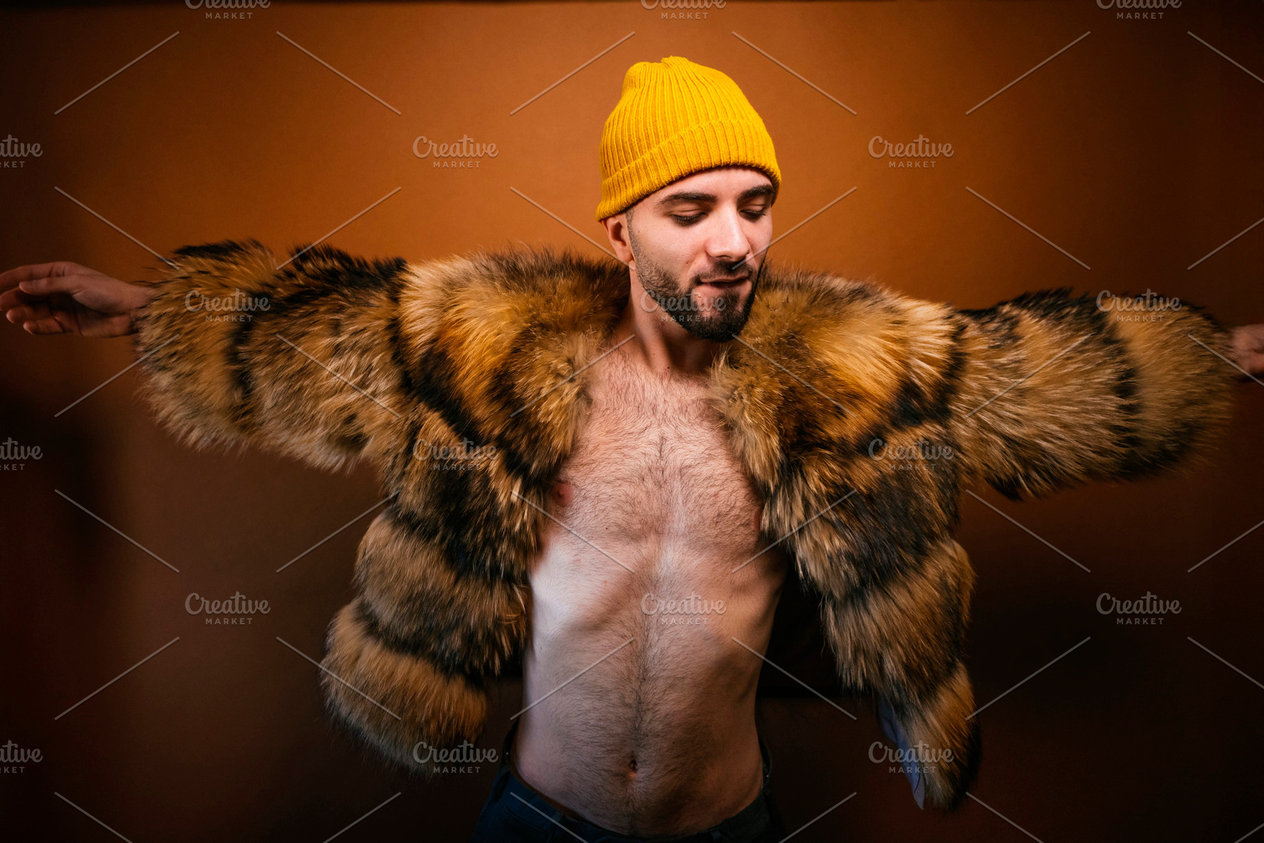 Confident man wearing fur coat with open arms, a Photo by karrastock