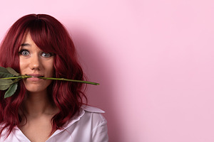 Young woman with red hair holding a red rose in her mouth, smili, a Person Photo by Ales Munt