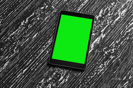 Black tablet with green screen on a wooden table mock up. Copy s, an Abstract Photo by Eugene_Photo