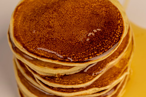a tower of small milk pancakes on a ceramic bowl with natural yellow bee honey,, a Photo by rsoollAI