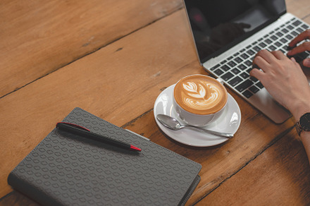 Close up of coffee cup with notebook and  woman hands using lapt, a Technology Photo by Ministocker