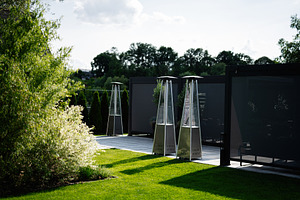 Modern outdoor space with patio heaters and greenery in natural sunlight, a Photo by AS photostudio