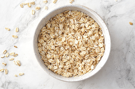 Oat flakes in bowl on white featuring oat, grain, and seed