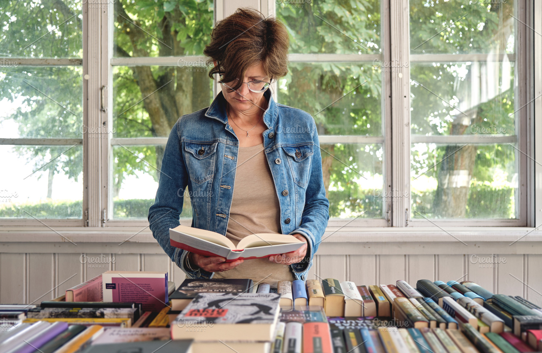 Middle aged woman reading a book, a Person Photo by BOOCYS