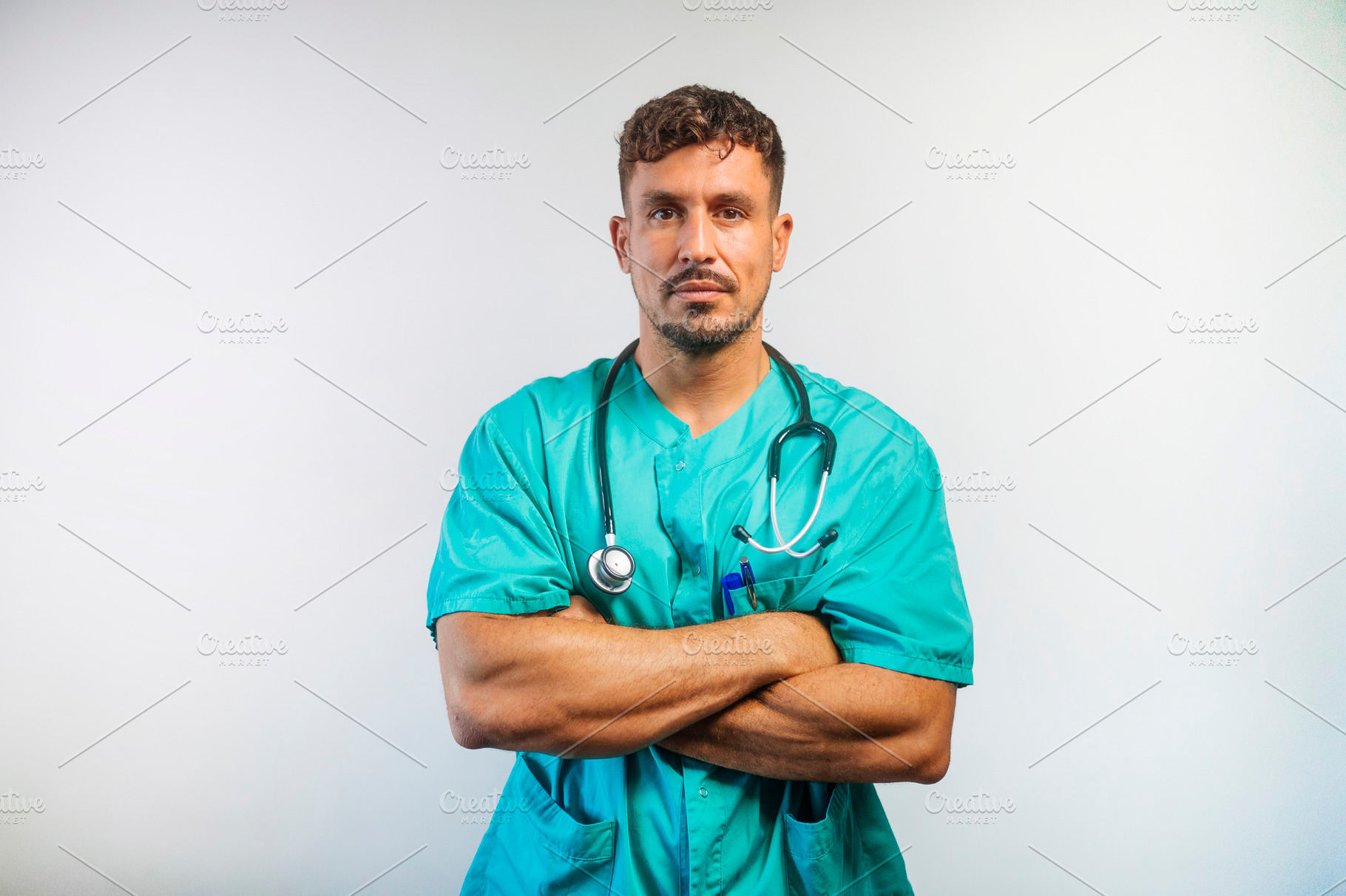 Confident male doctor in scrubs with arms crossed, looking at camera., a Person Photo by karrastock