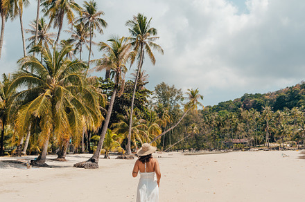 A woman in a hat enjoys the summer sun on a beautiful tropical b, a Holiday Photo by Art Rachen