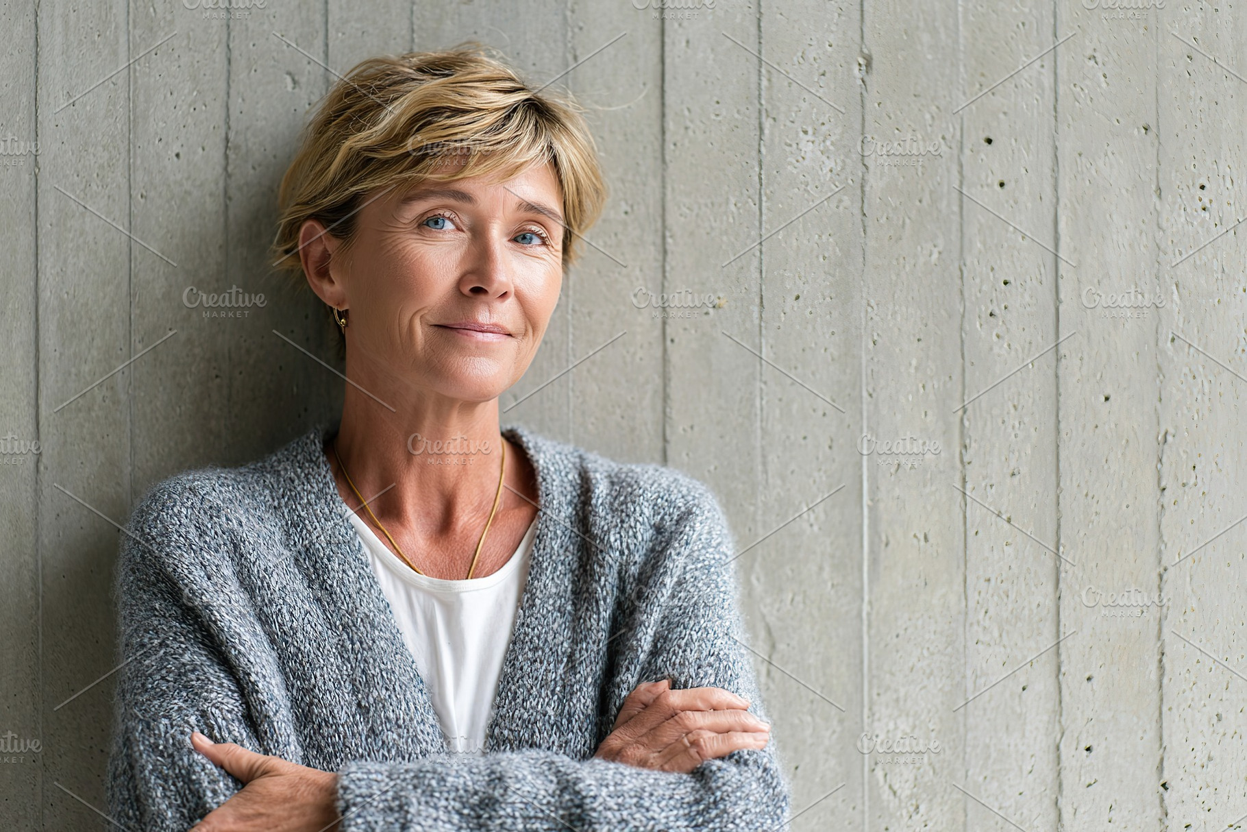 Middle-aged woman with a subtle smile, posing against a textured gray wall, a Person Photo by AlyaAnd
