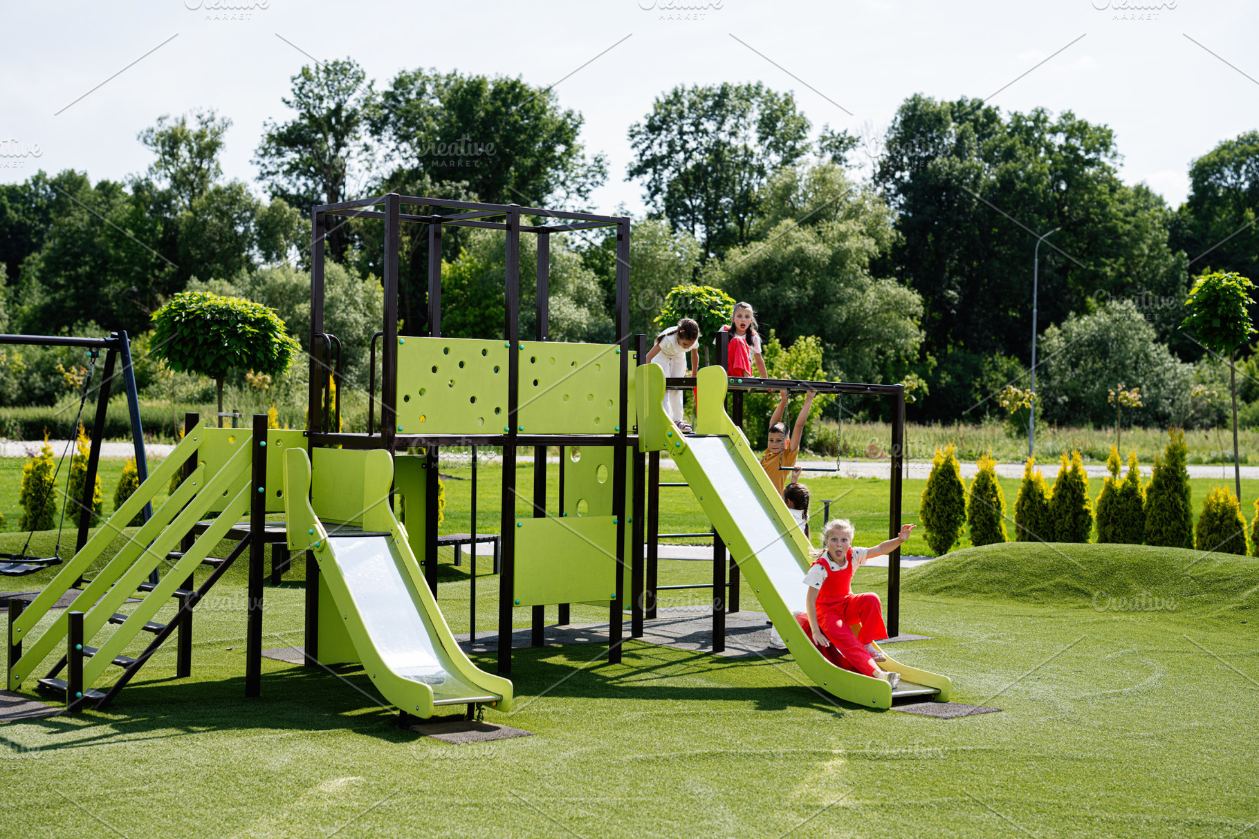 Children playing on a green playground on a sunny summer day, a Photo by AS photostudio