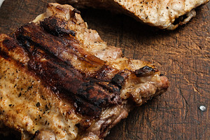 Two pieces of fried meat on an old wooden board, a Food & Drink Photo by ndanko