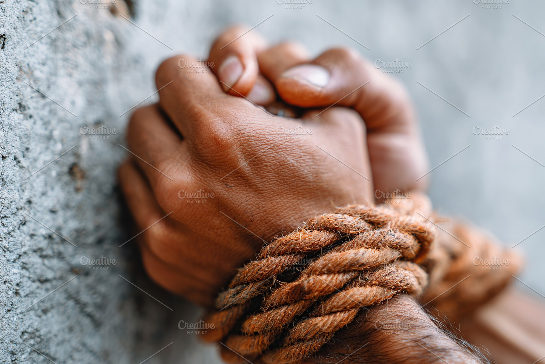 Hands bound with rope against a rough wall depicting a sense of restraint and s, a Photo by AlyaAnd