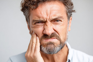 Middle-aged man with hand on cheek in pain because of a toothache, a Person Photo by AlyaAnd