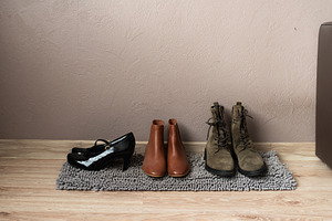 Shoes neatly arranged on rug near wall in home interior, an Industrial Photo by MDBildes
