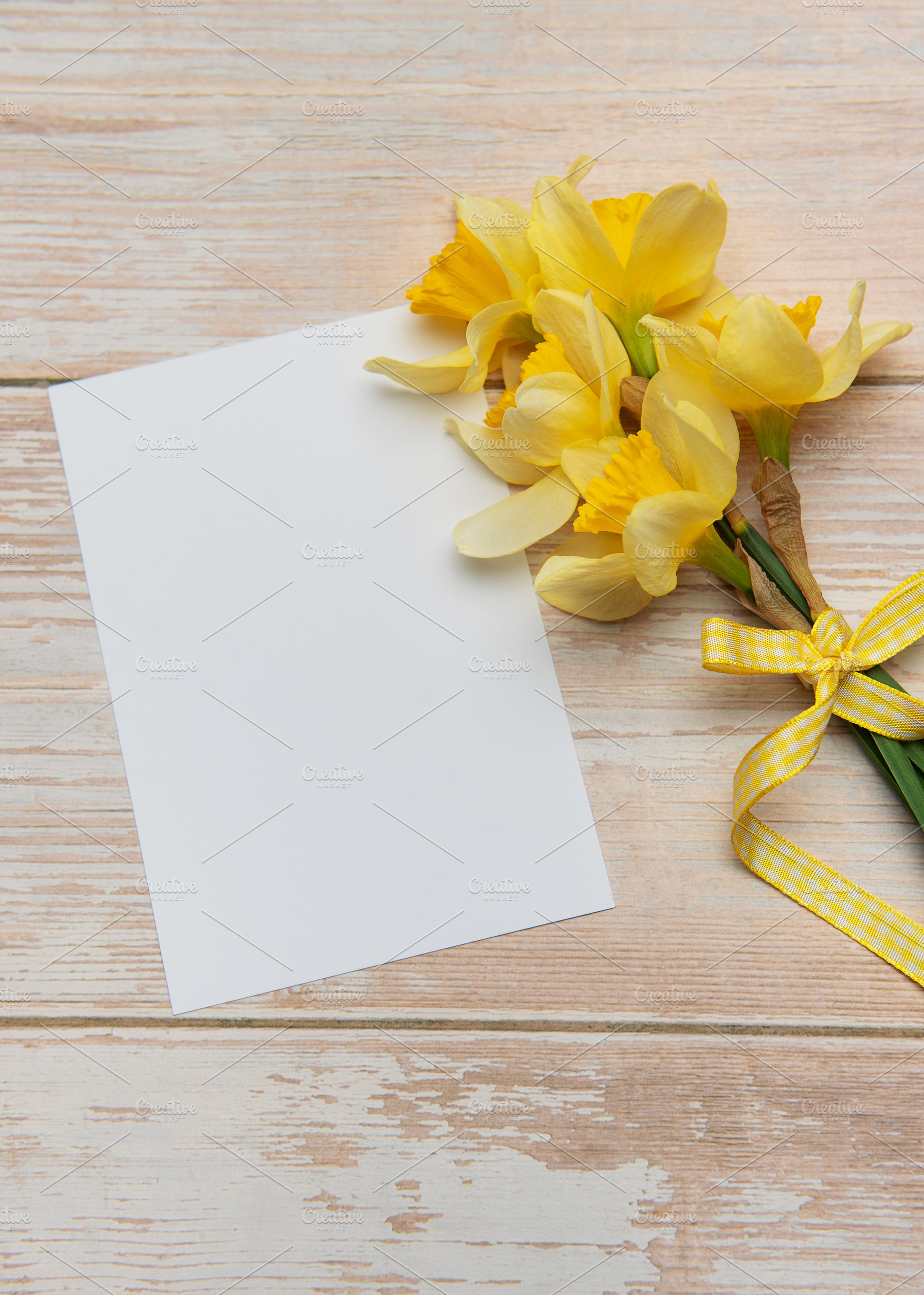 Bouquet of daffodils and blank card lying on wooden table, a Holiday Photo by Olena Rudo