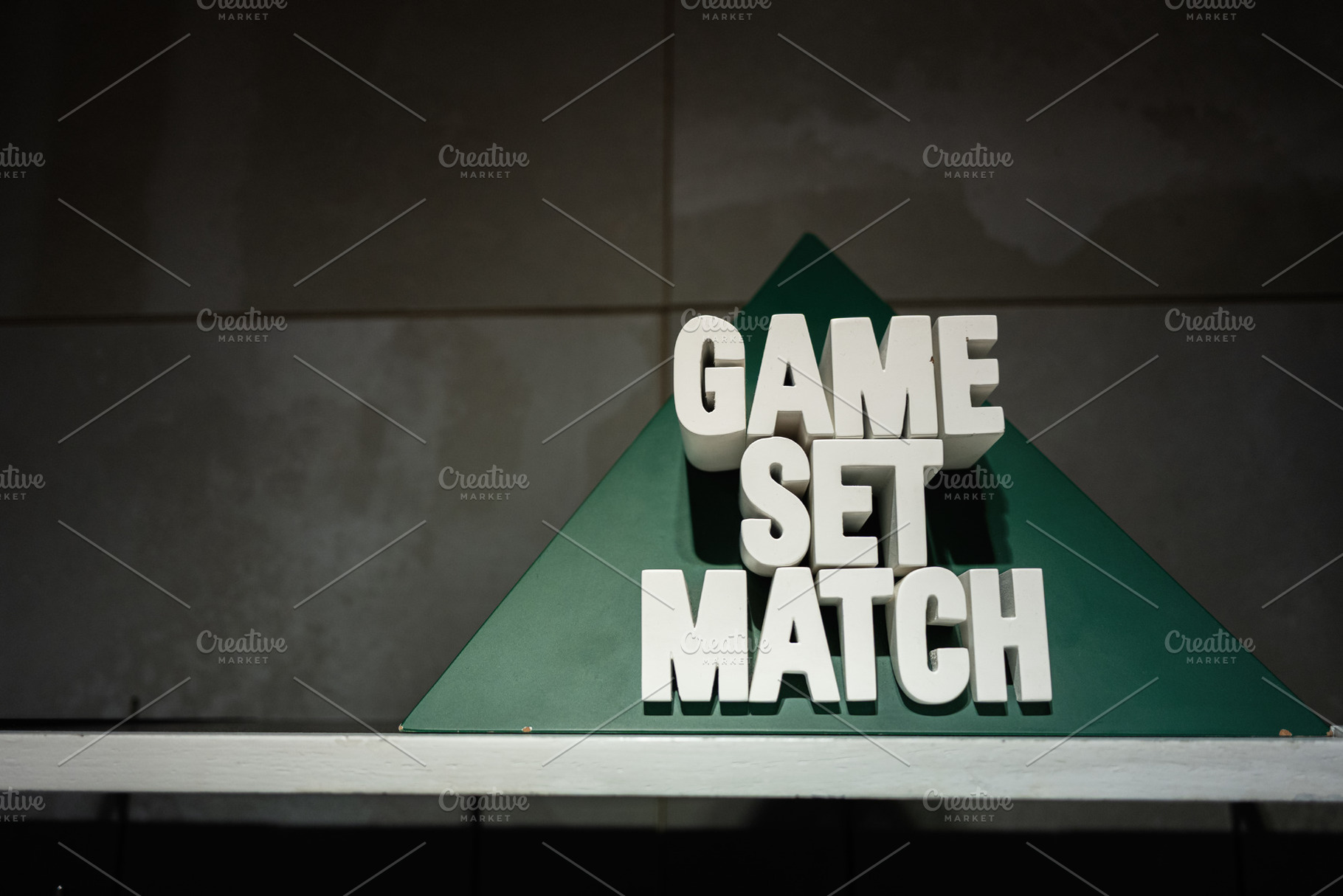 Minimalist sign with 'Game Set Match' displayed on a green triangle, a Photo by AS photostudio
