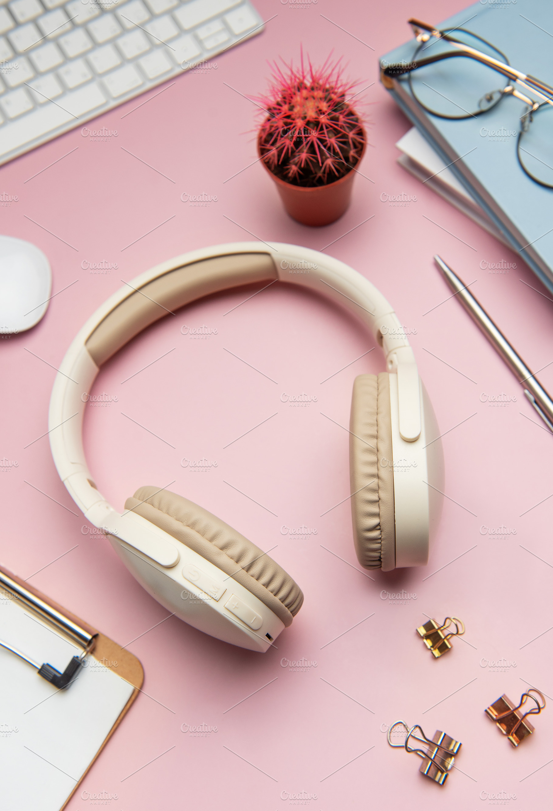 Wireless headphones laying on pink desk with keyboard, mouse, an, a Business Photo by Olena Rudo