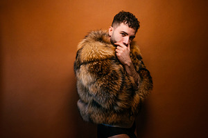Confident man posing in luxurious fur coat, a Photo by karrastock