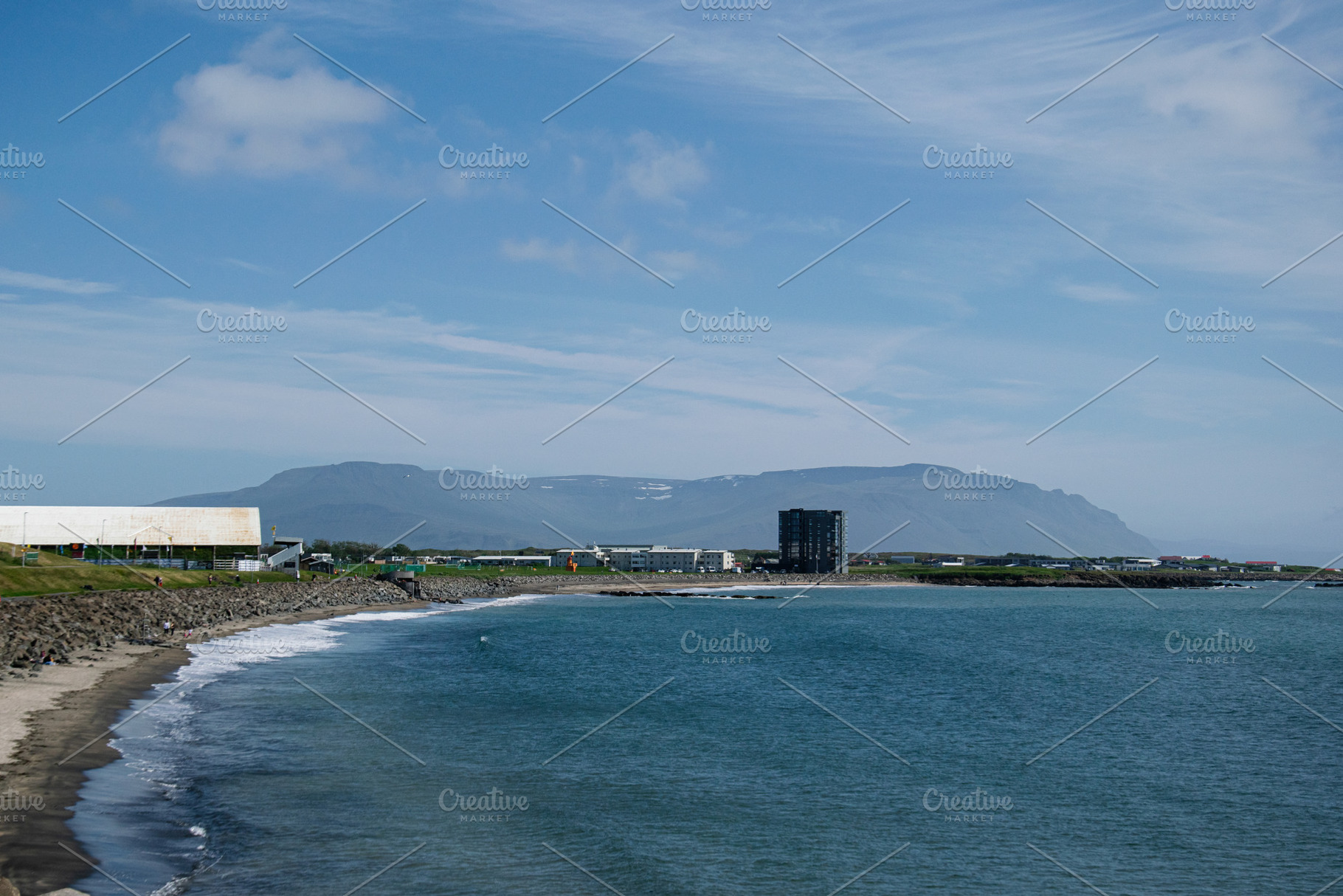 Scenic coastal view of Akranes beach with distant mountains under sunny sky, a Photo by AS photostudio